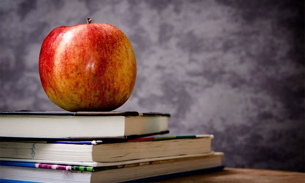An apple sits atop three books